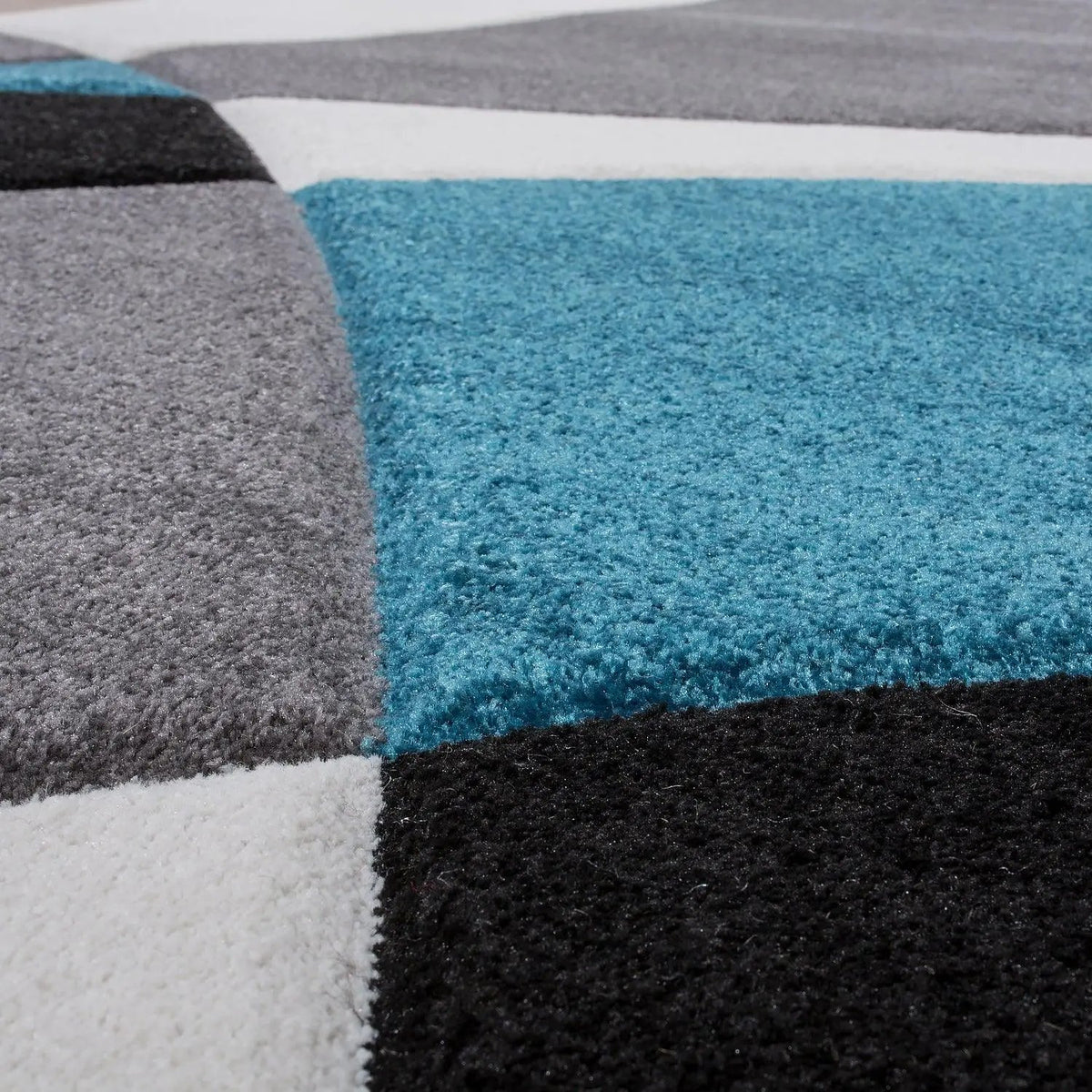 Close-up of a geometric patterned rug with blue, gray, black, and white squares.
