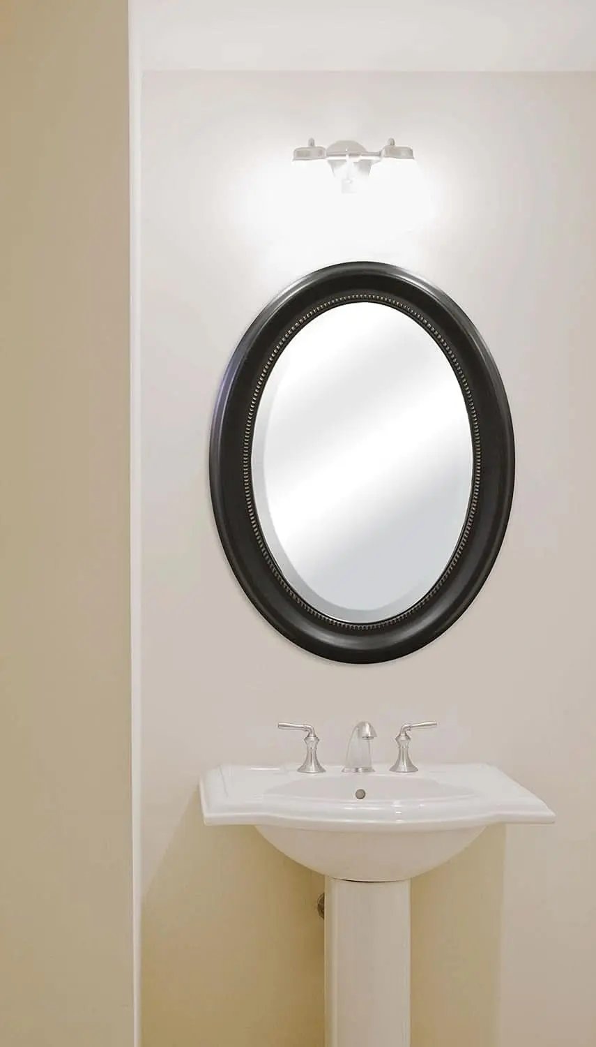 Bathroom with a round mirror and sink against a beige wall.