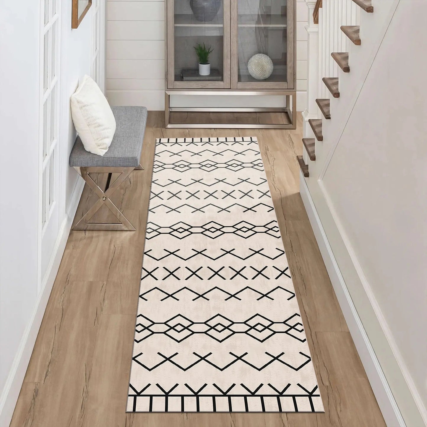 Long rectangular rug with black geometric pattern on a wooden floor in a home setting.