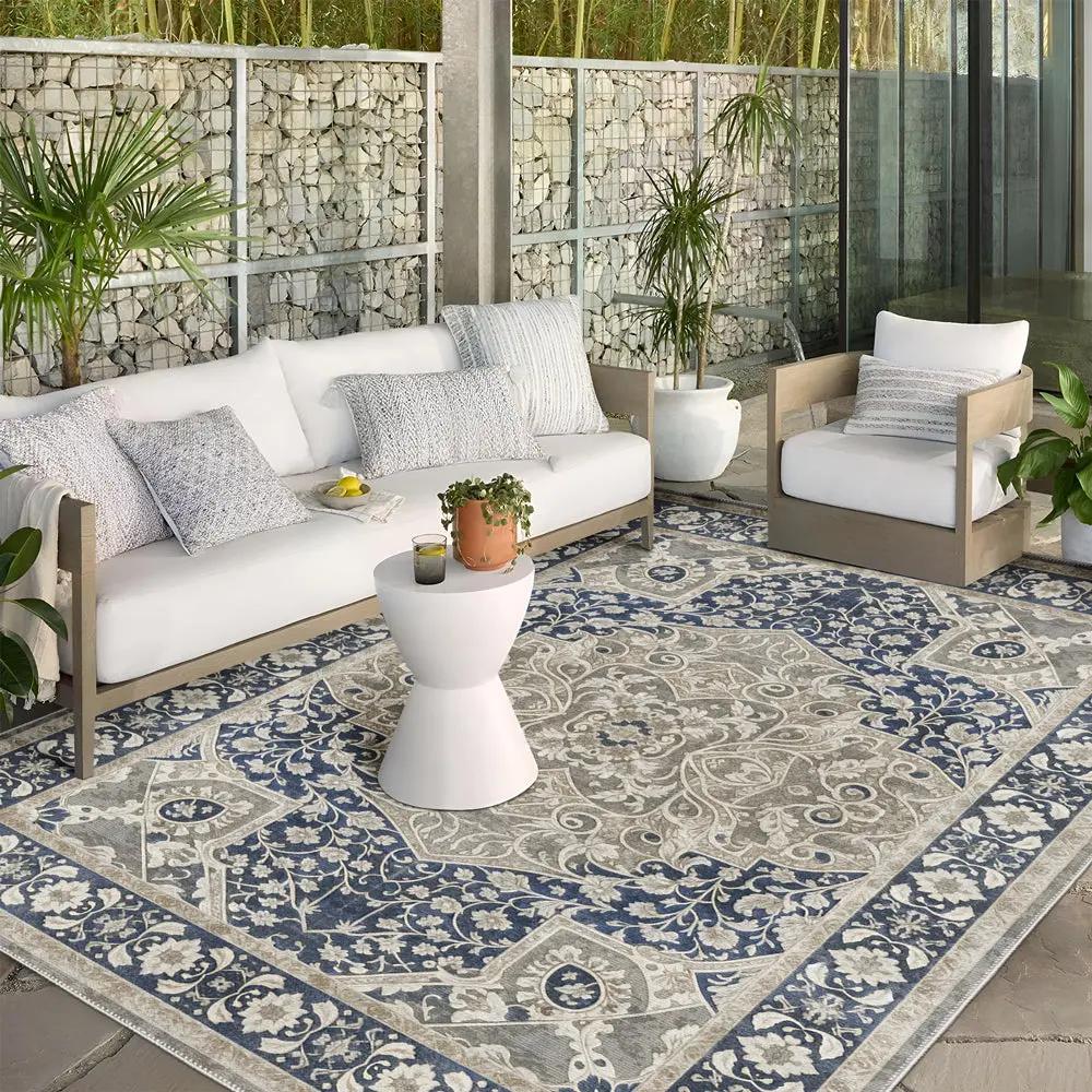 Outdoor patio with patterned rug, white sofa, and chairs.