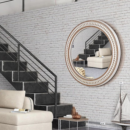 Round decorative mirror on a white brick wall with a staircase and sofa in the background