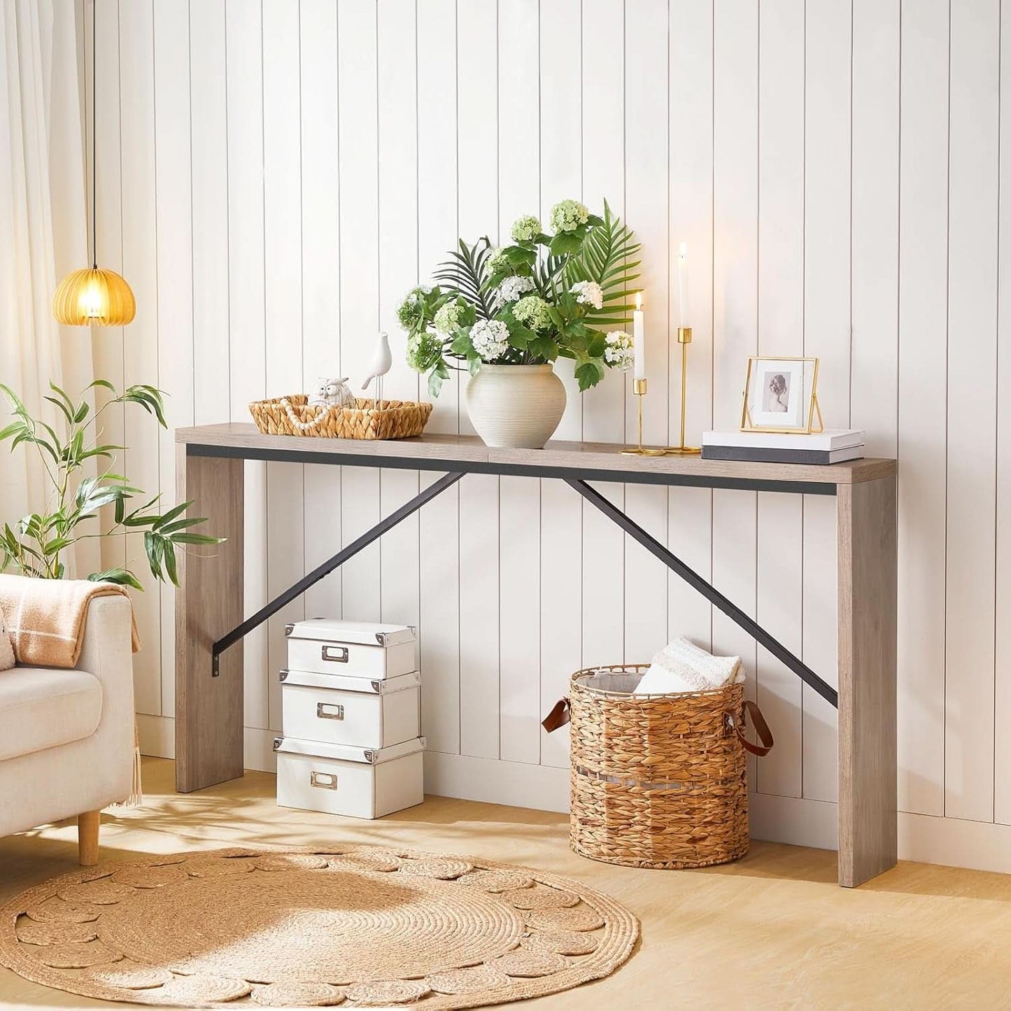 Modern interior with a console table, plants, and decorative items against a white paneled wall.