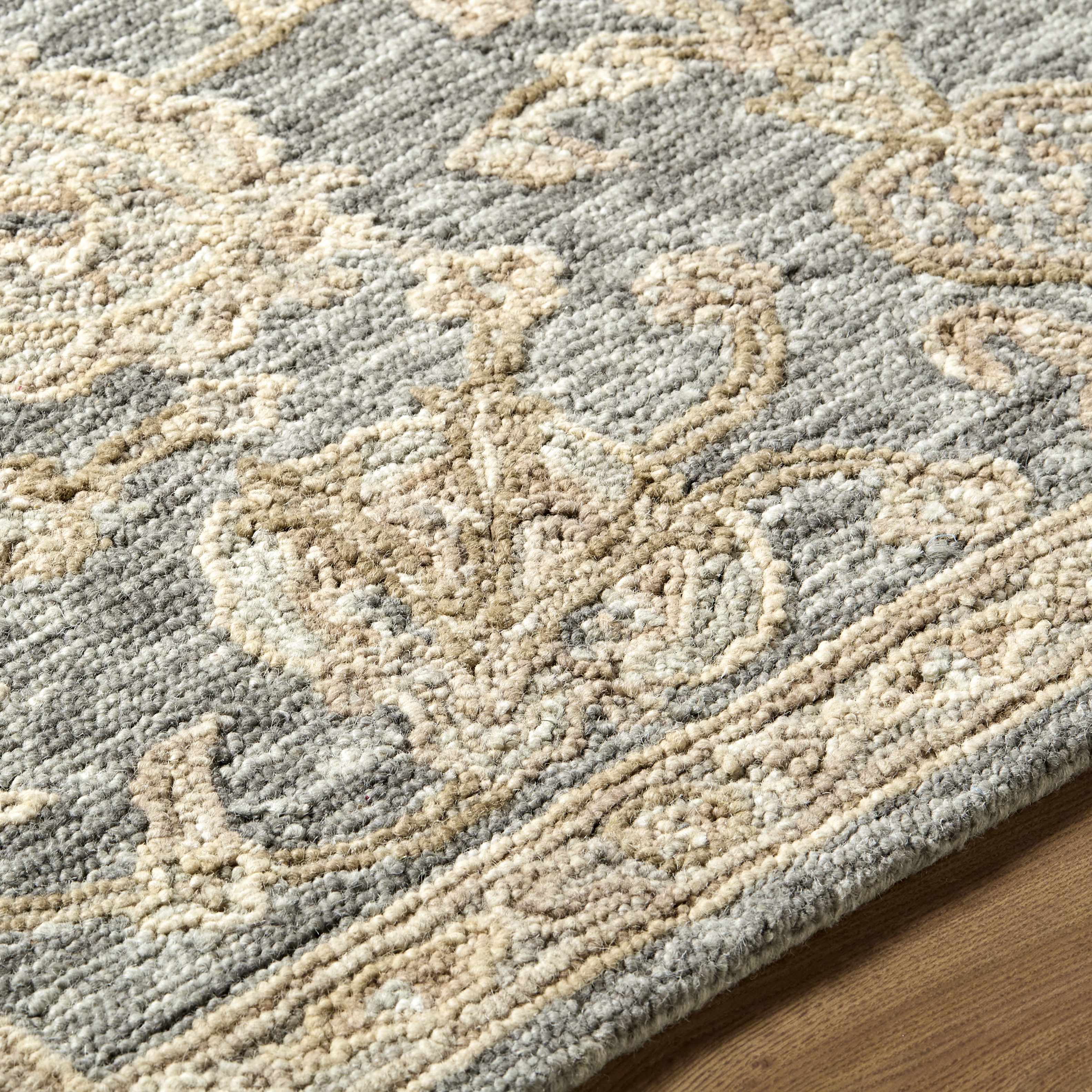 Close-up of a textured area rug with intricate patterns on a wooden floor.
