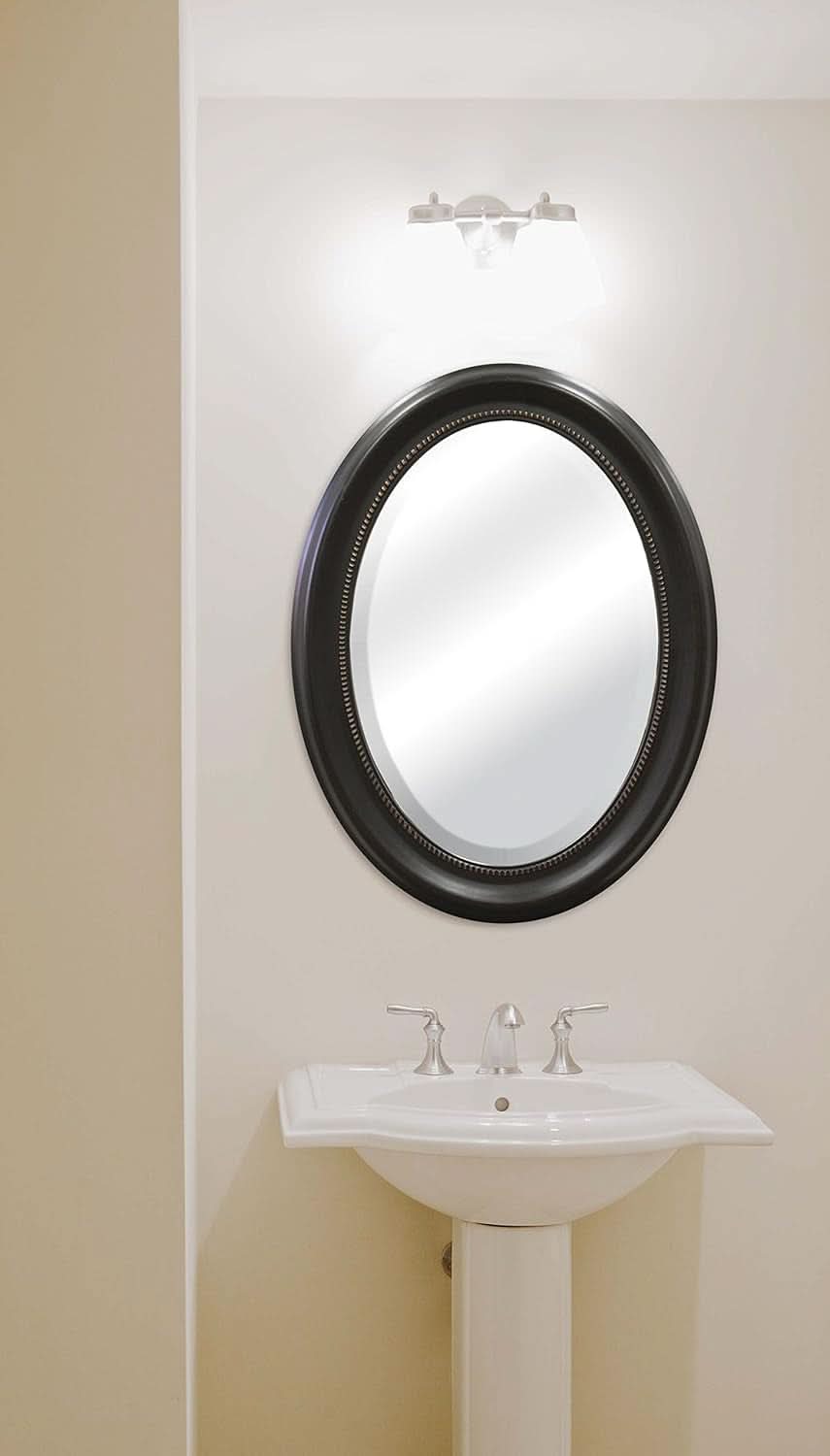 Bathroom with a round mirror and sink against a beige wall.