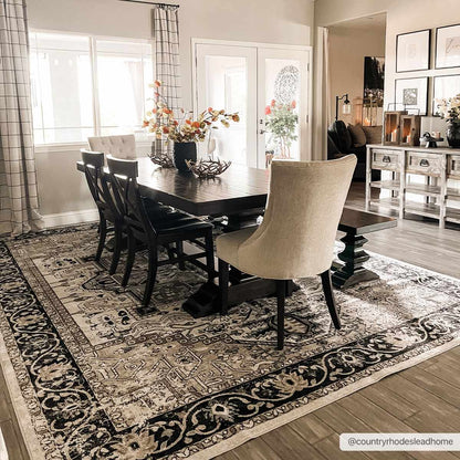 Dining room with a wooden table and chairs on a patterned rug.