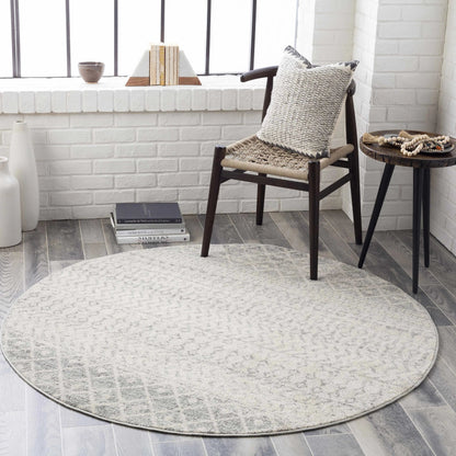 Round rug in a room with a chair and small table.