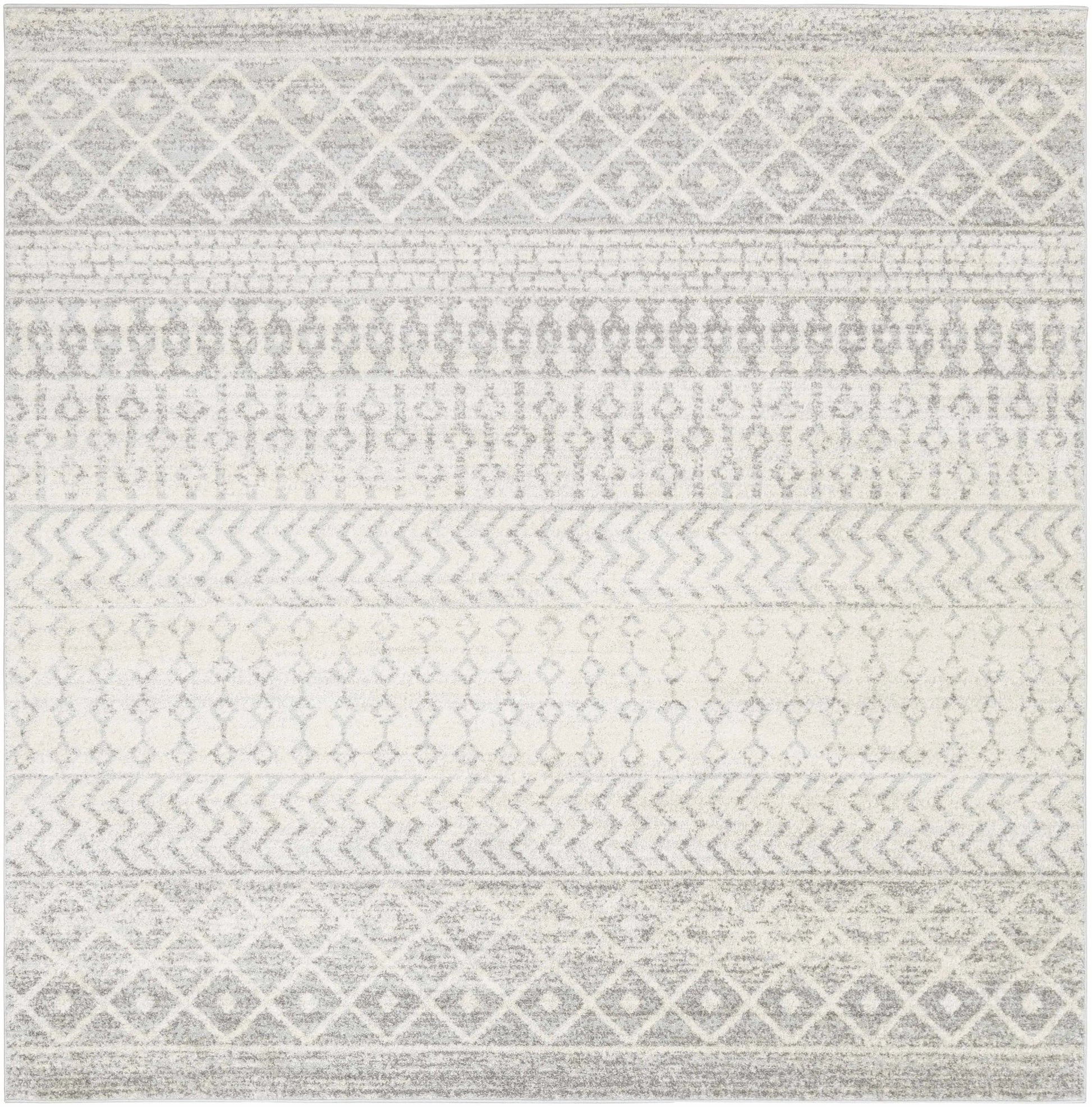 A square area rug with a distressed geometric pattern in shades of gray and off-white, featuring horizontal bands of diamond, chevron, and dot motifs.