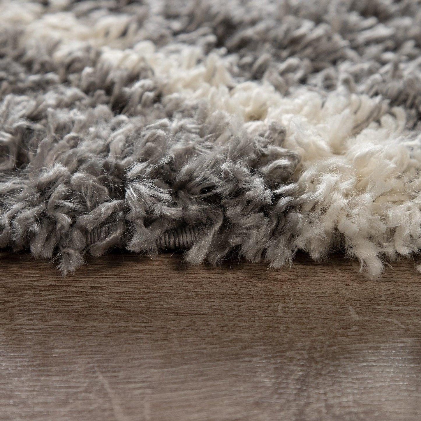 Close-up of a textured gray and white rug on a wooden floor.
