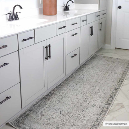 Bathroom with white cabinets, black fixtures, and a patterned rug on the floor.