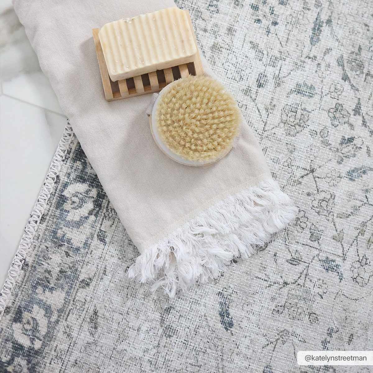 Bar of soap on a wooden block with a natural bristle brush on a textured fabric background