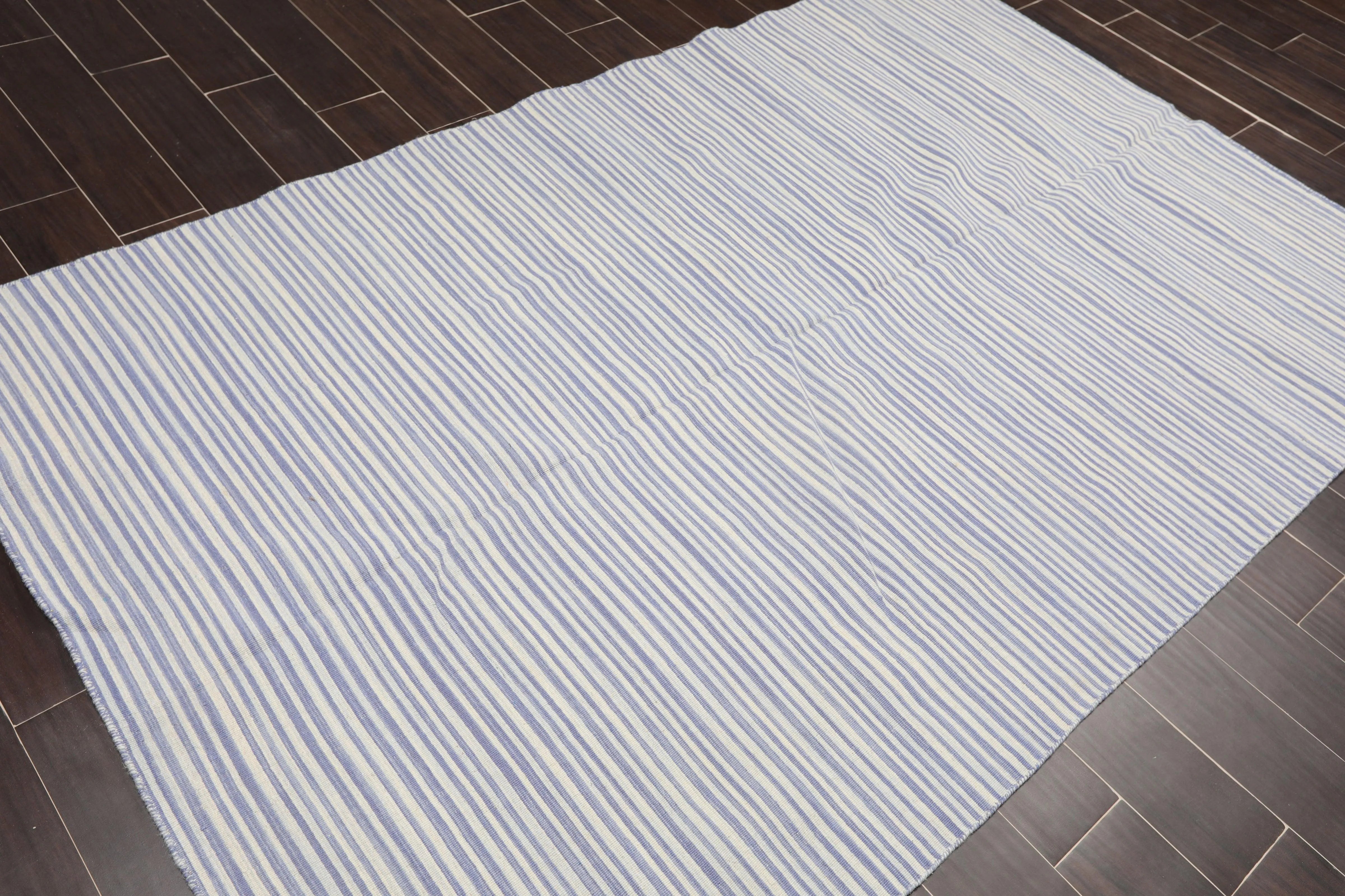 White rug with blue stripes on a wooden floor