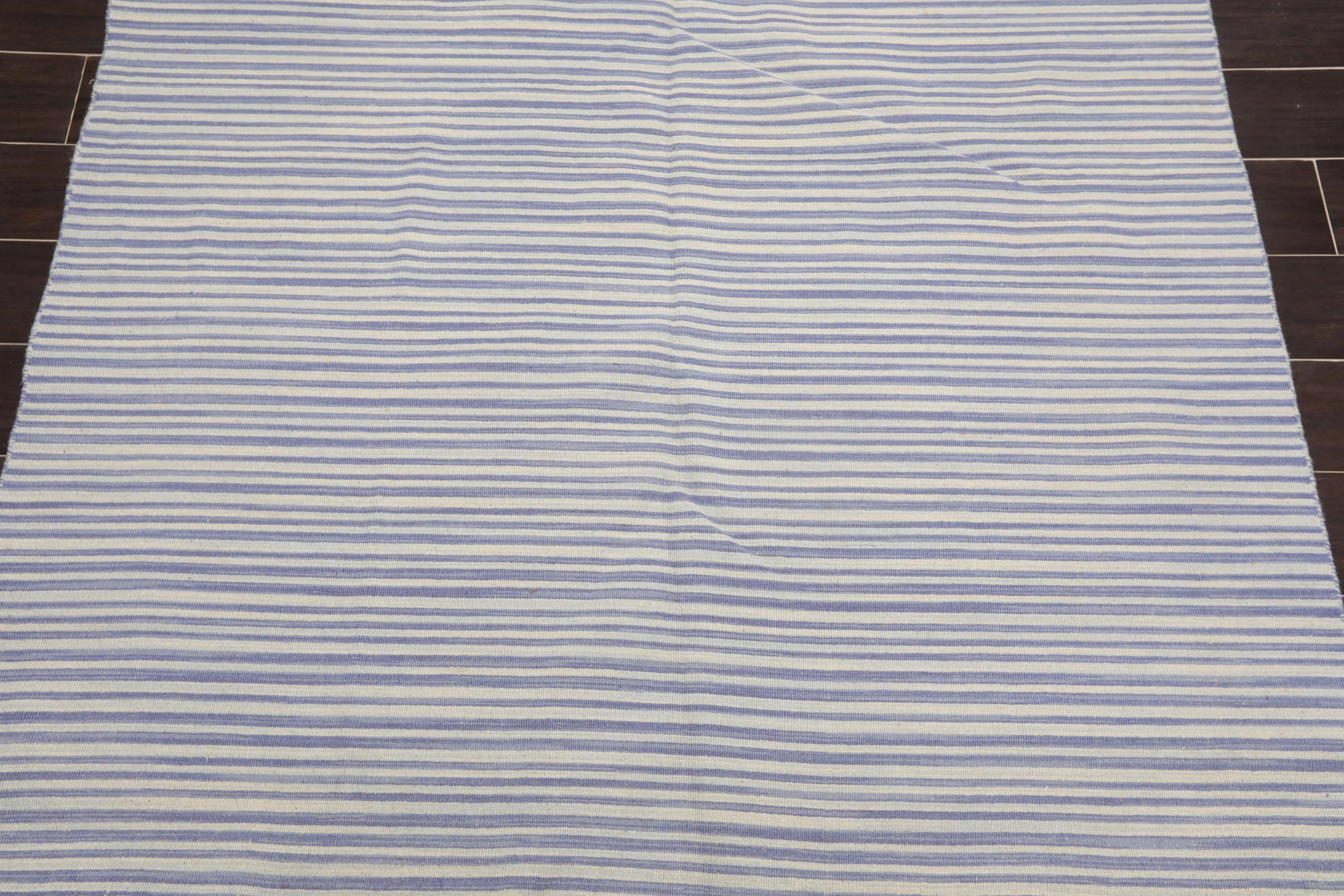 Striped rug with blue and white horizontal lines on a wooden floor.