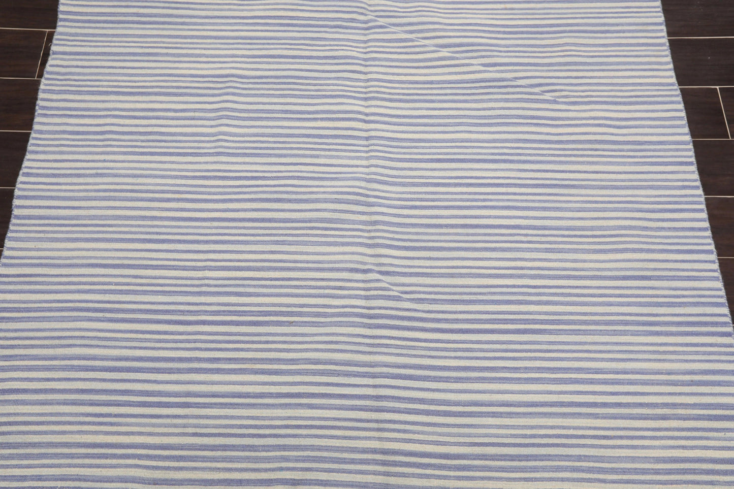 Striped rug with blue and white horizontal lines on a wooden floor.