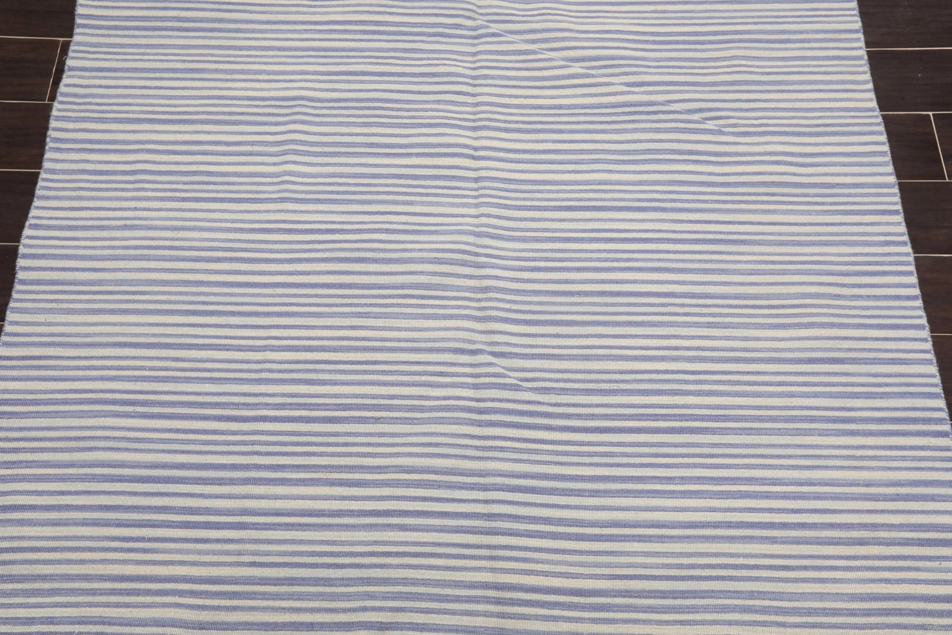 Striped rug with blue and white horizontal lines on a wooden floor.
