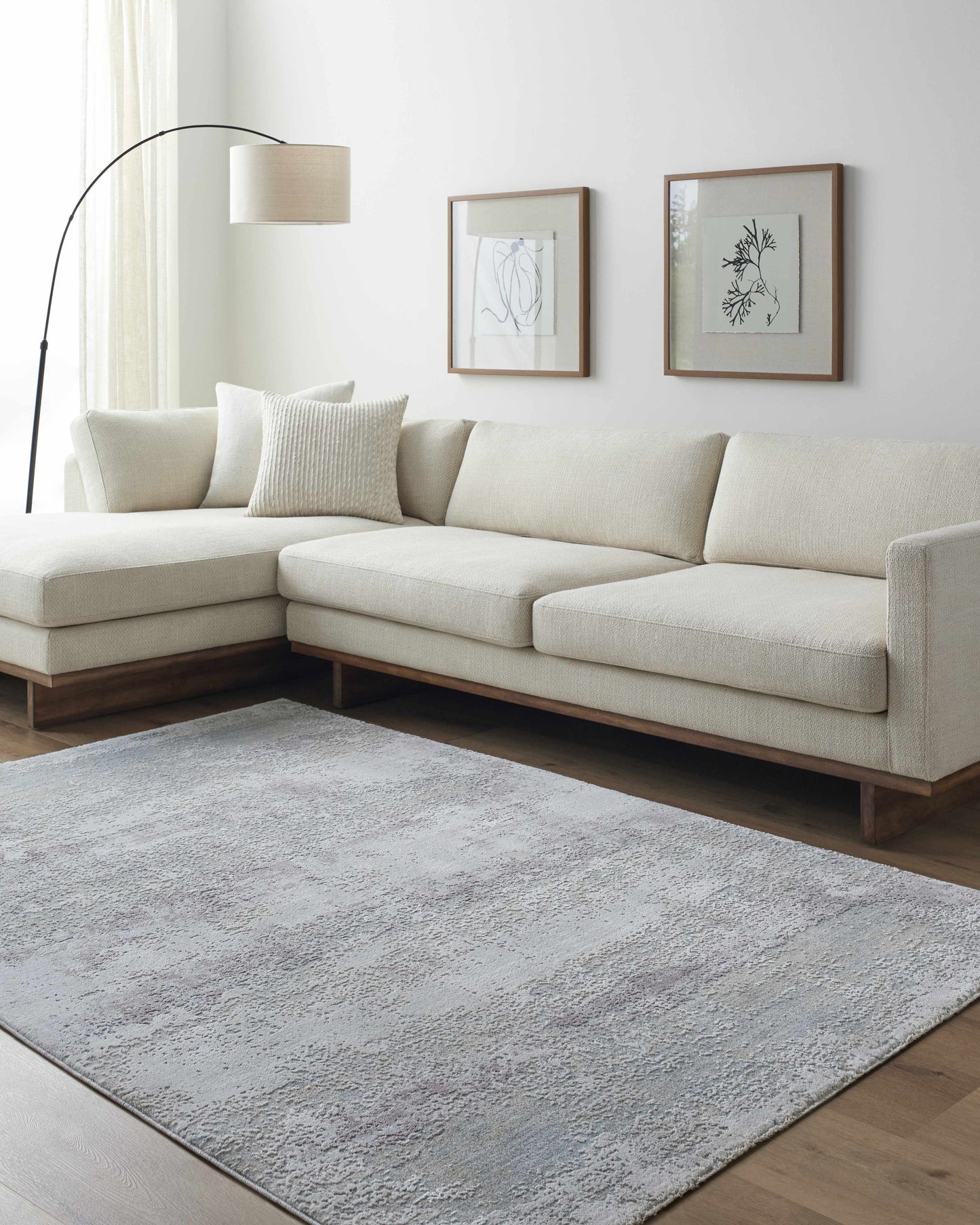 Modern living room with a beige sectional sofa, gray rug, and framed artwork on the wall.