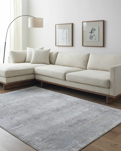 Modern living room with a beige sectional sofa, gray rug, and framed artwork on the wall.