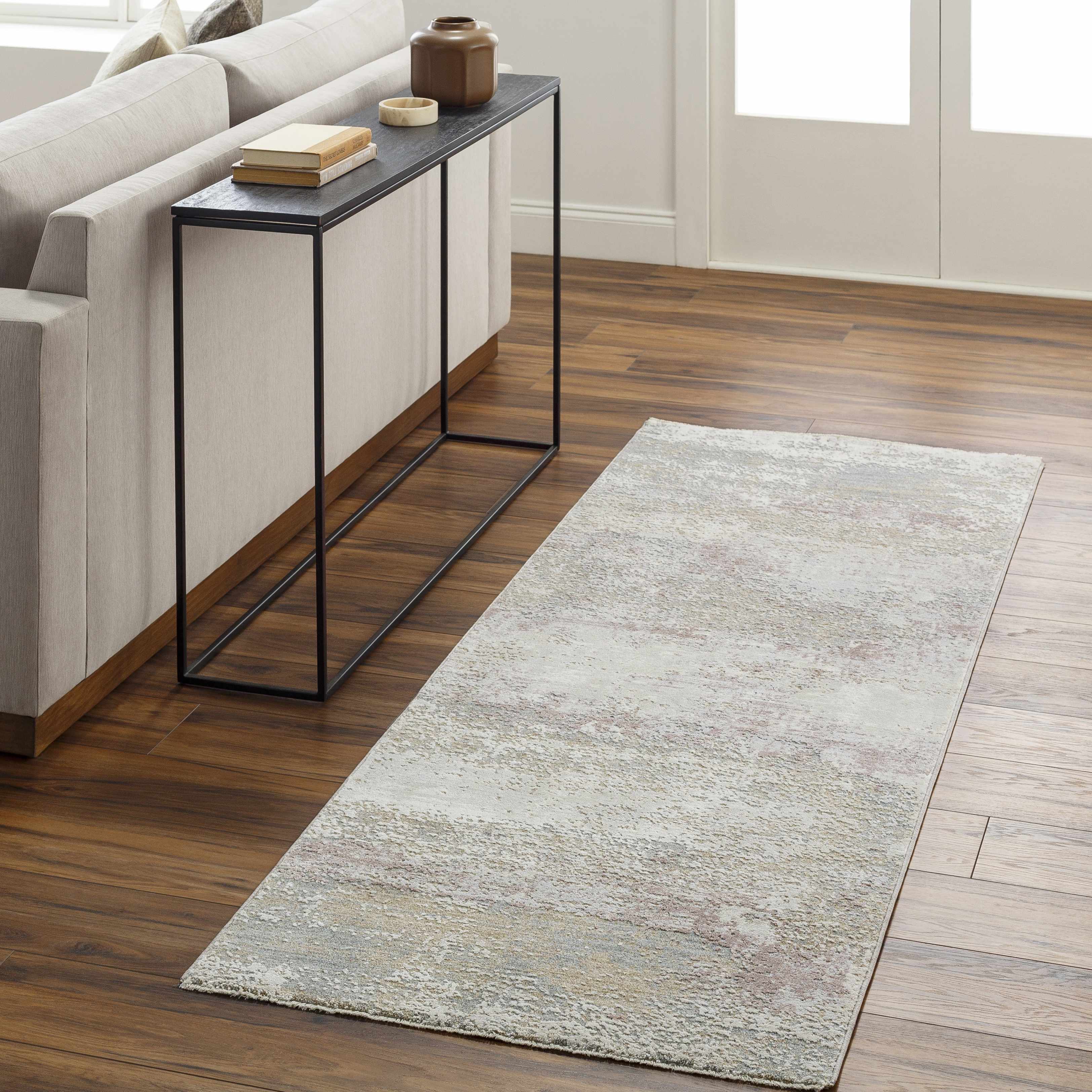 Living room with a gray area rug on wooden floor and a side table.