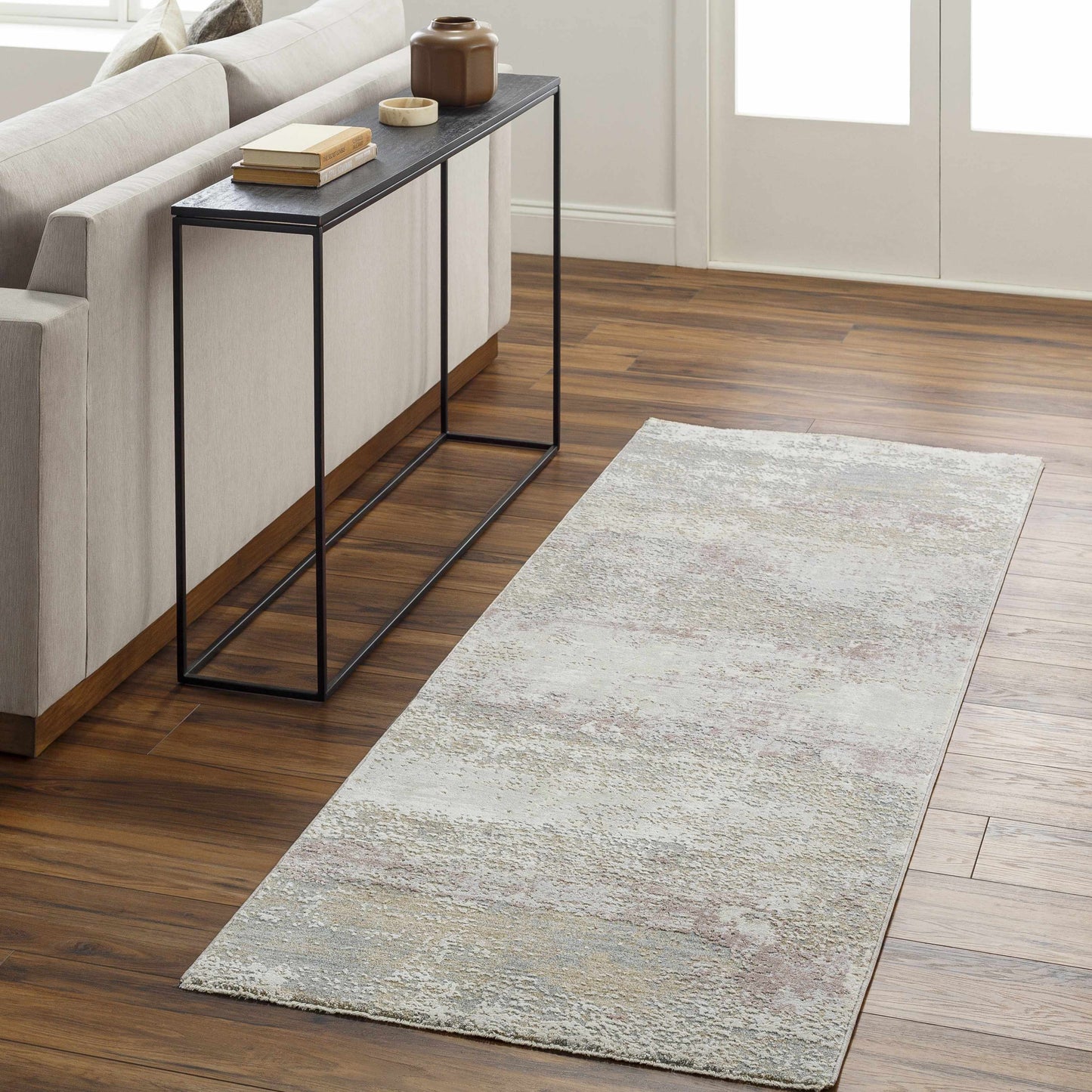 Living room with a gray area rug on wooden floor and a side table.