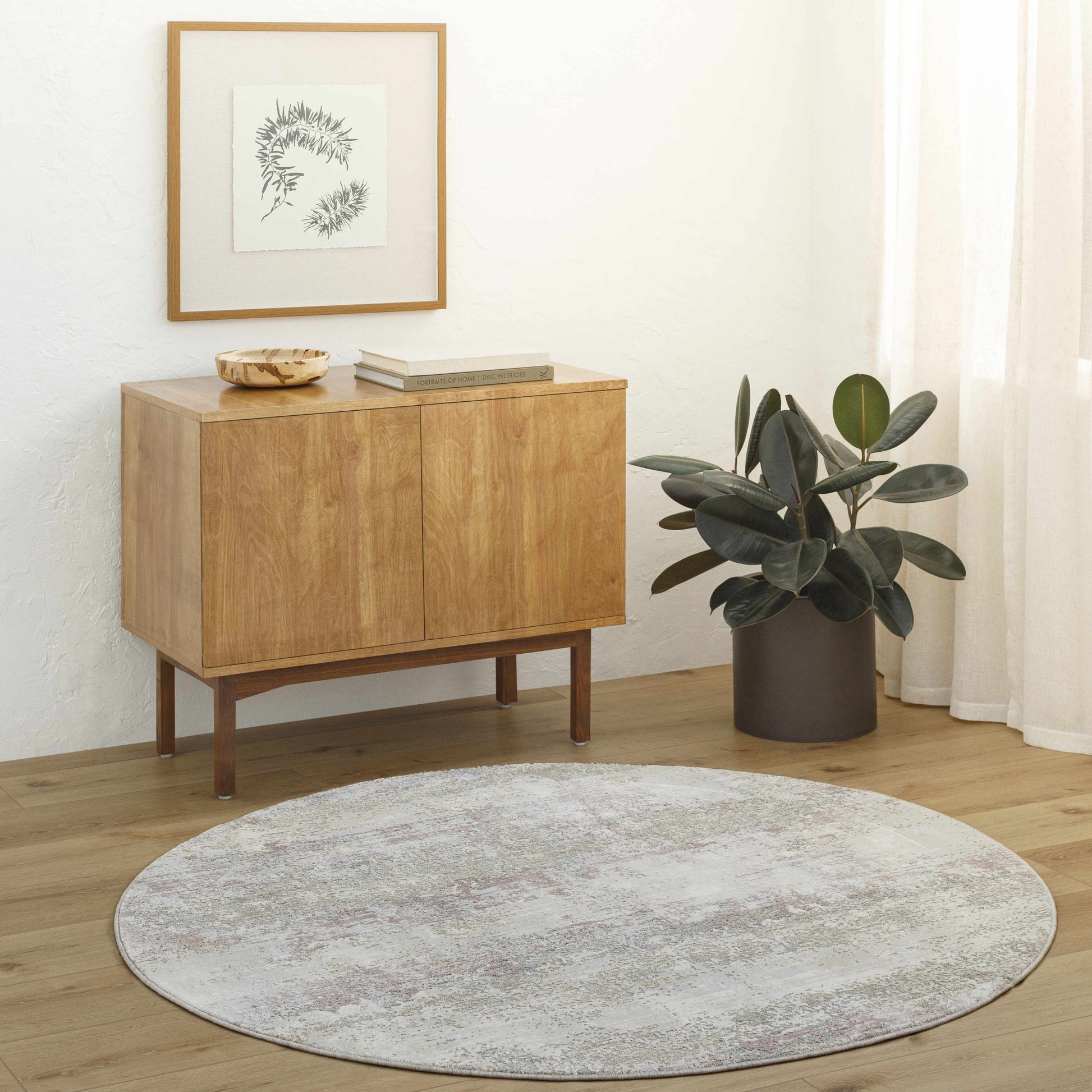 Wooden sideboard with decorative items in a room with a round rug and plant.