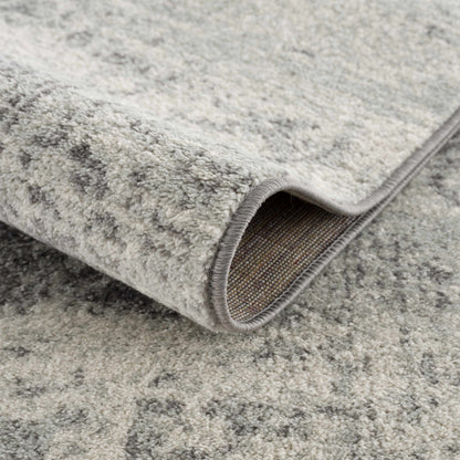 Close-up of a rolled-up gray rug on a textured surface