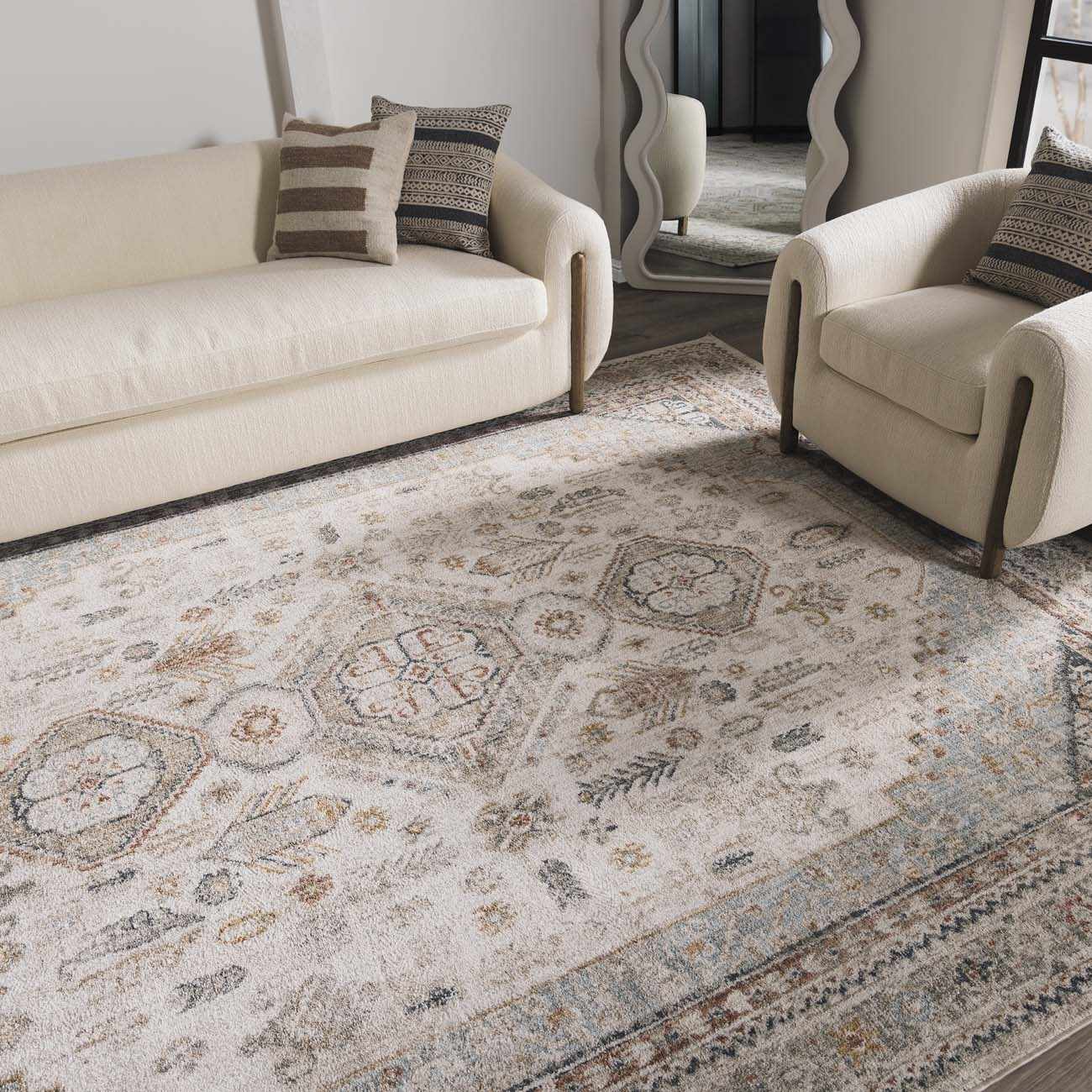 Living room with a patterned rug, beige sofa, and armchair.