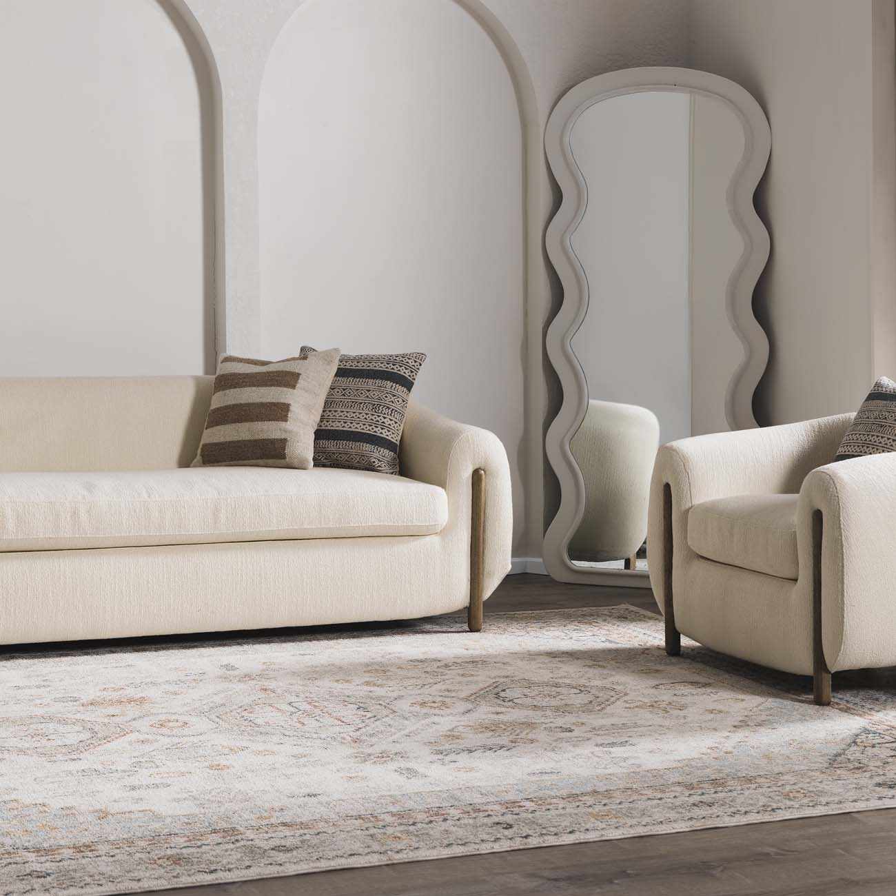 Beige sofa and armchair with decorative pillows in a stylish living room.