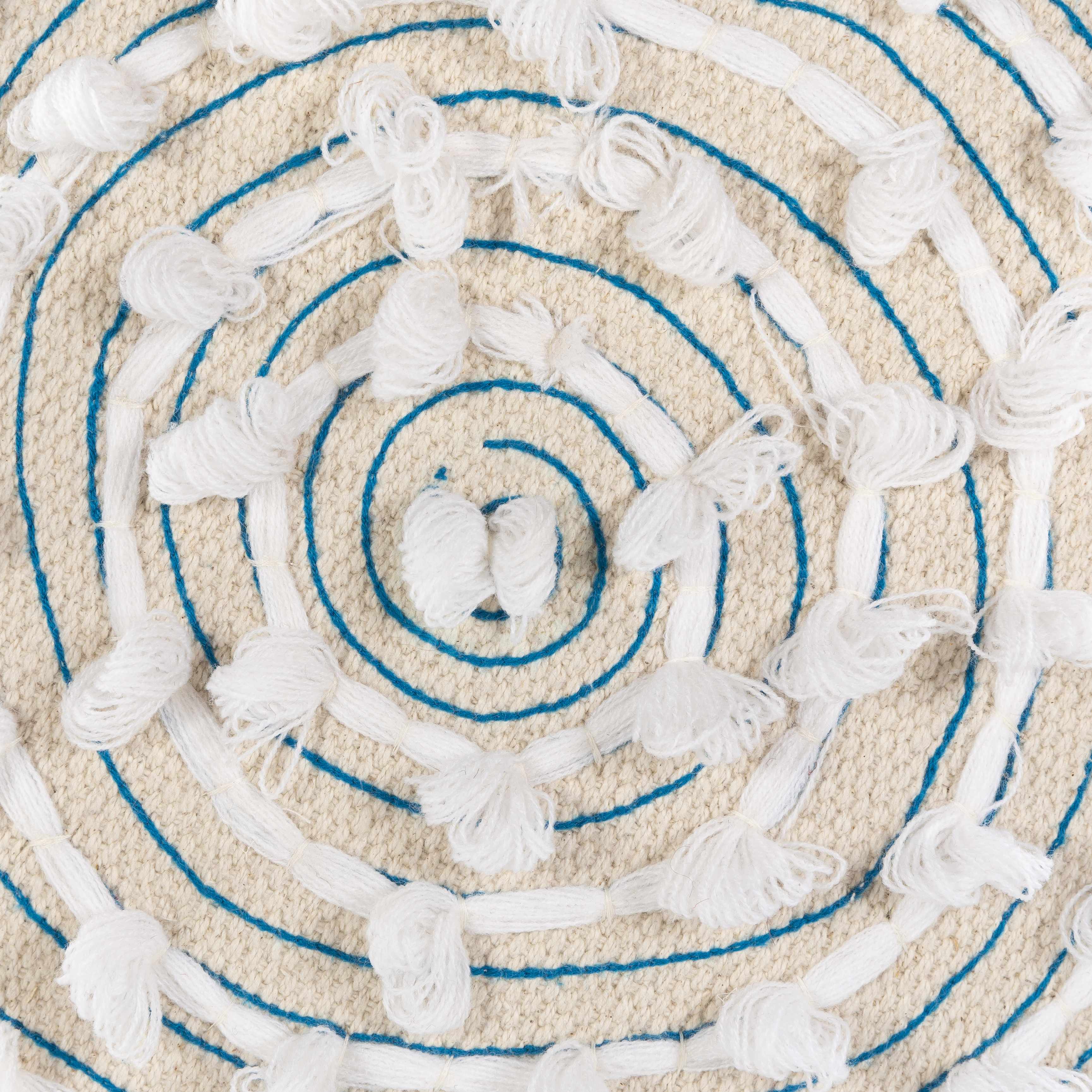 Close-up of a textured round rug with concentric circles and tassels.