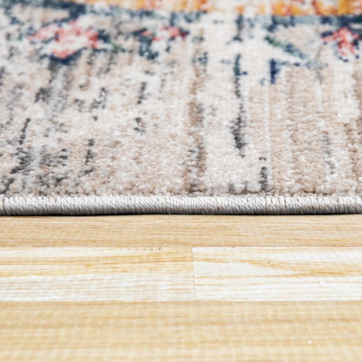 Close-up of a rug with a floral pattern on a wooden floor.
