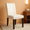 White chair with black legs against a beige wall with a wooden side table.