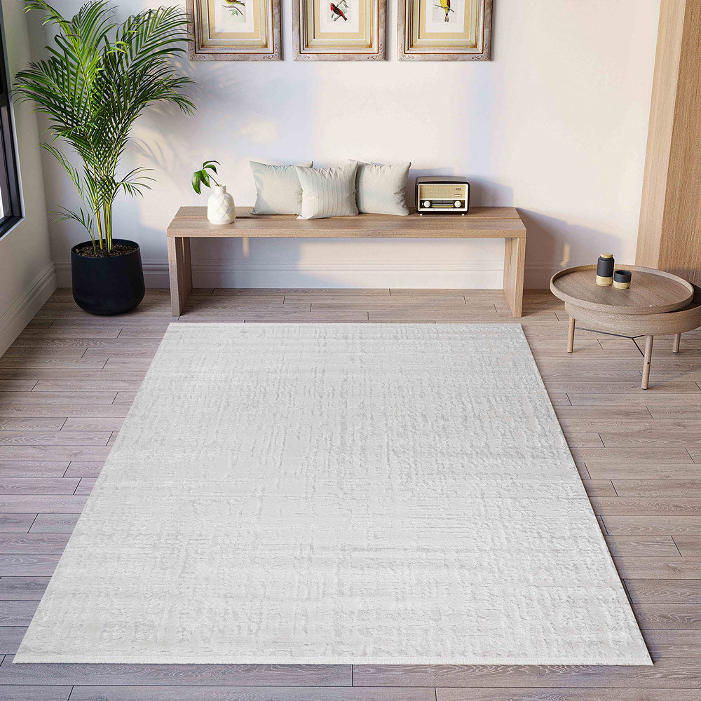 White rug on a wooden floor with a living room setup including a coffee table and plants.