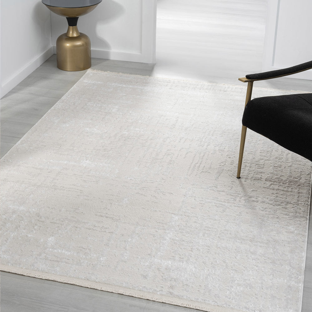 Gray textured rug in a room with a black chair and gold side table.