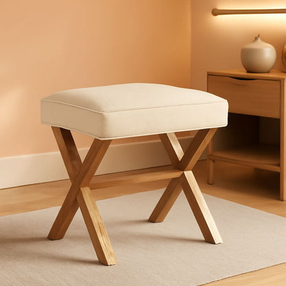 Beige cushioned stool with wooden legs in a room setting.