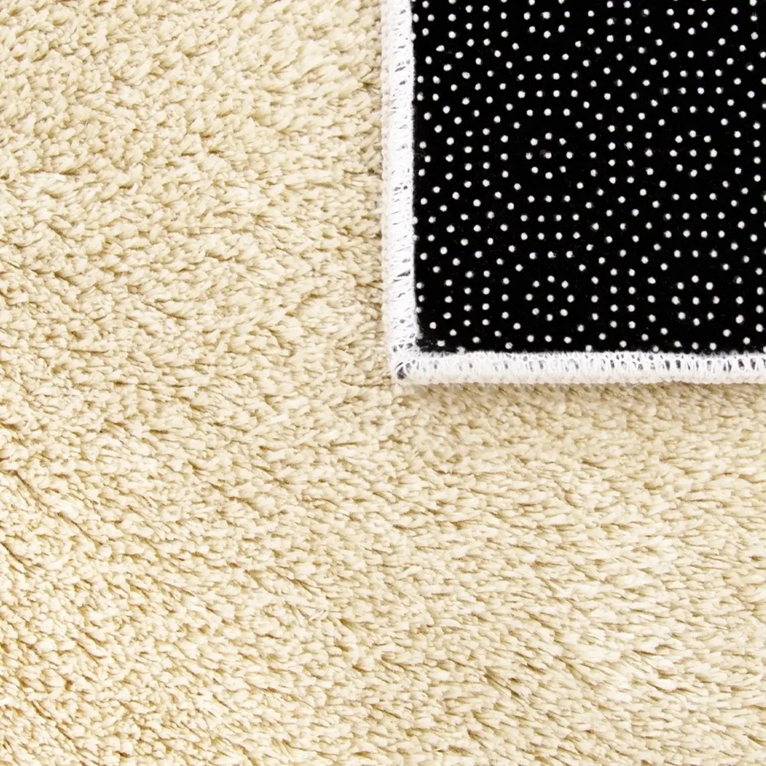 Beige carpet with a black and white polka dot rug corner.