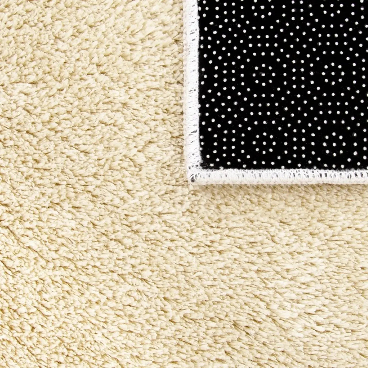 Beige carpet with a black and white polka dot rug corner.