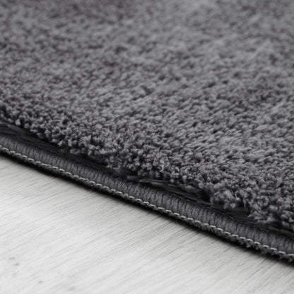 Close-up of a gray textured rug on a light wooden floor.