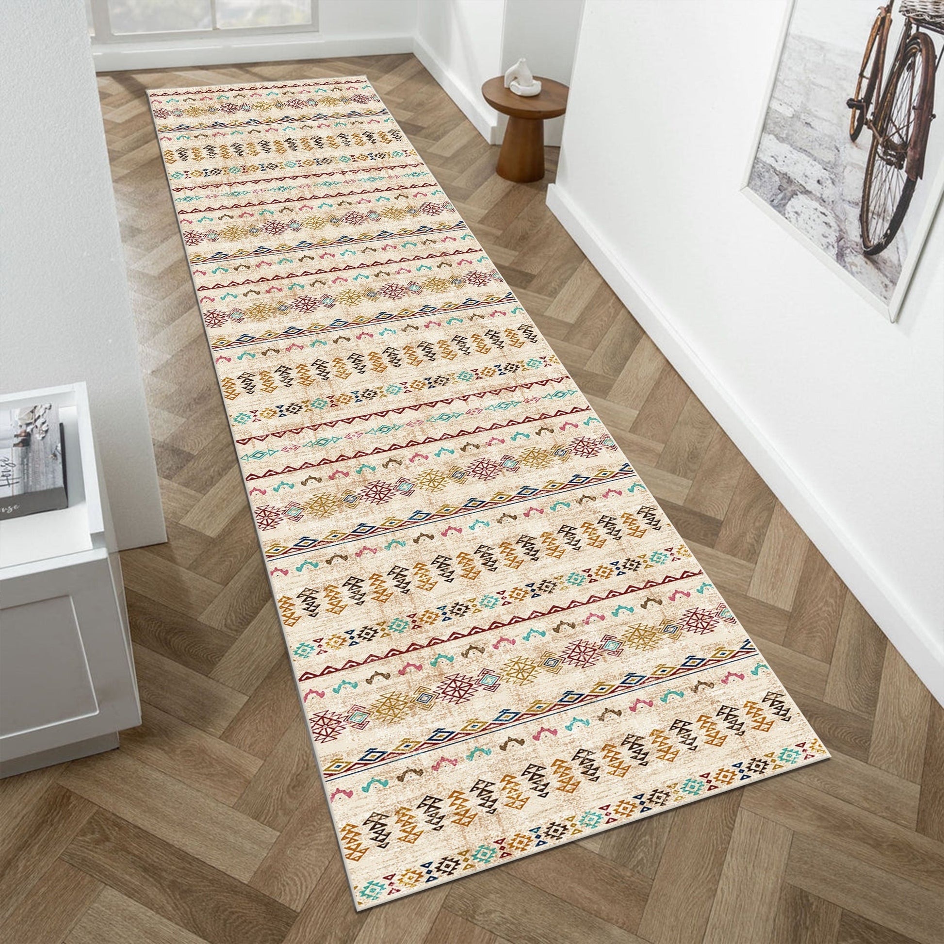 Long, patterned rug on a wooden floor in a room with a bicycle and small table.