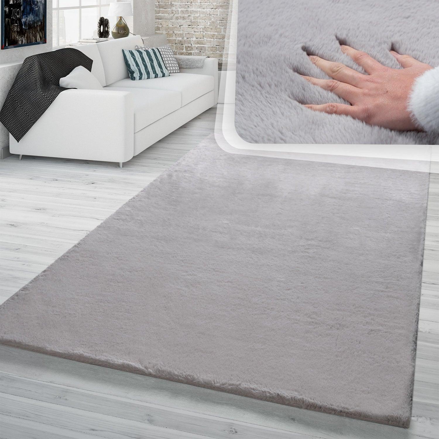 Gray rug on a wooden floor with a white sofa and decorative pillows in the background.