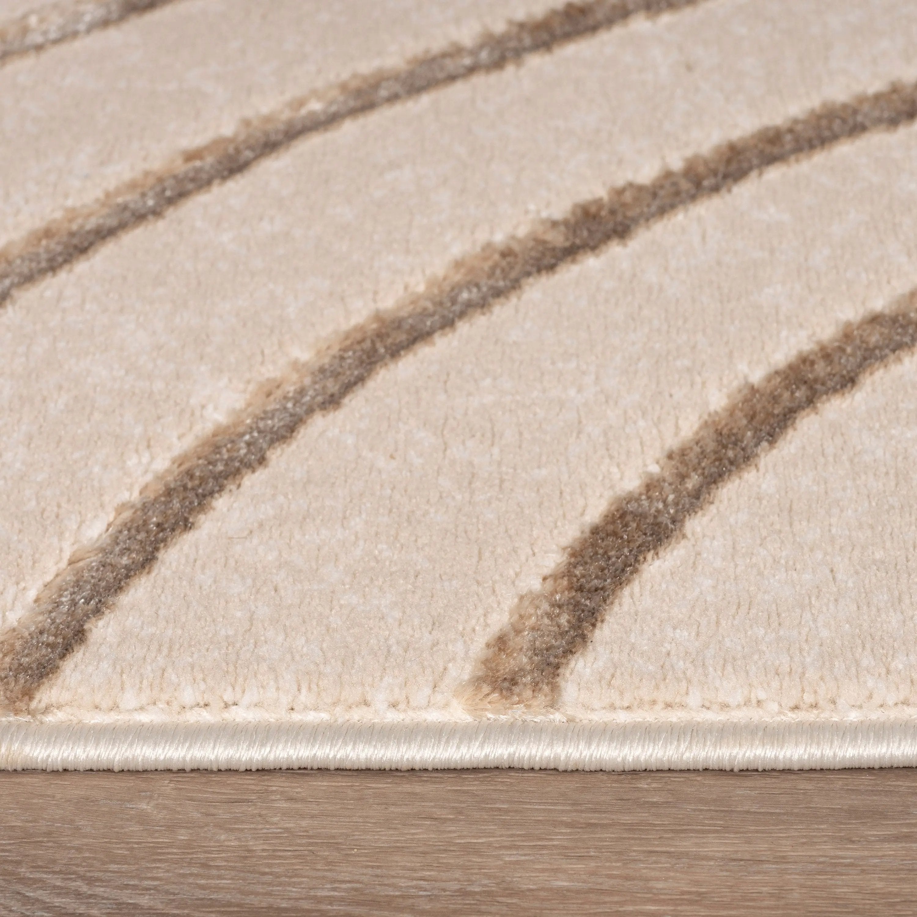 Close-up of a beige rug with brown stripes on a wooden floor.