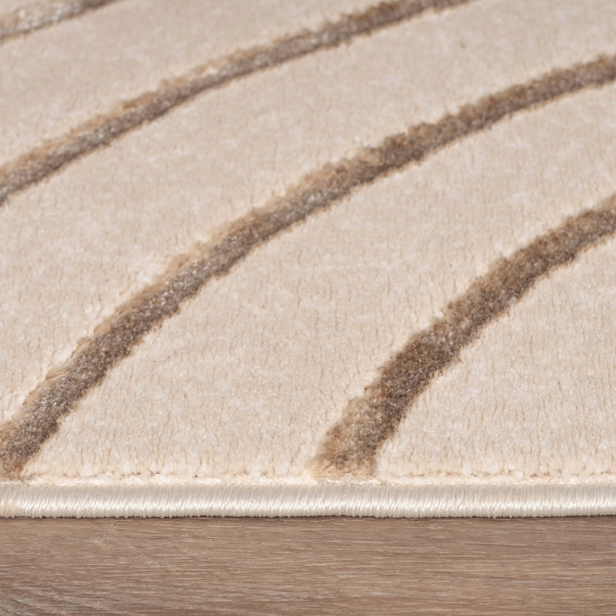 Close-up of a beige rug with brown stripes on a wooden floor.